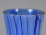 a blue glass vase with a silver rim on a table