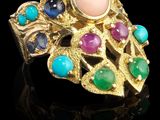 gros plan d'une bague en or avec des pierres multicolores