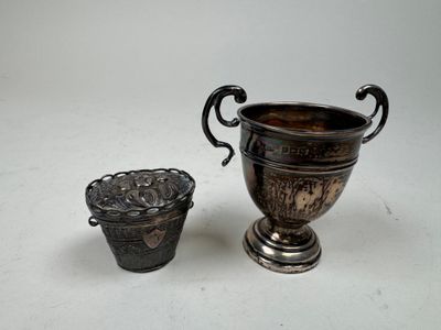 une coupe en argent et un vase en argent posés sur une table