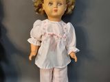 a doll that is standing next to a cloth bag