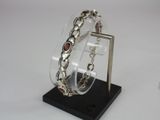 silver bracelet with garnett on display on a black stand