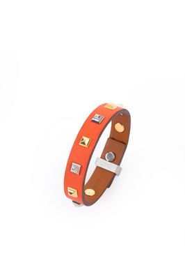 an orange leather bracelet with gold studs on a white background