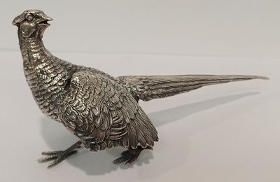 figurine de faisan plaquée argent, posée sur un socle, sur un fond blanc
