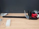 a red and black hedger on a table next to a tool