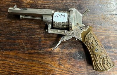 un vieux revolver posé sur une table en bois, avec une étiquette dessus