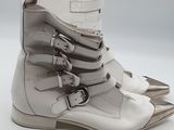 pair of white leather boots with silver buckles on a white surface