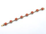 un gros plan d'un bracelet orné de perles orange sur un fond blanc