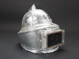 an old silver helmet on a black surface with a black background