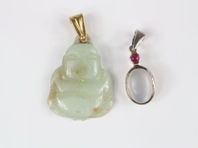 un petit pendentif en forme de Bouddha et une bague posés l'un à côté de l'autre
