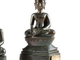 deux statues de Bouddha en bronze, assises sur un socle en bois
