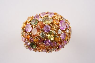 une image représentant une bague ornée de pierres multicolores sur un fond blanc