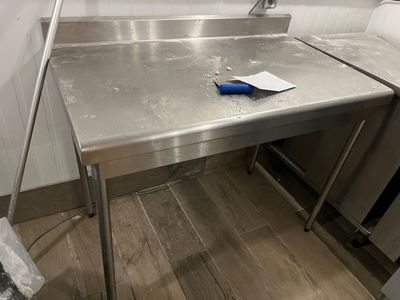 une table en acier inoxydable sur laquelle se trouve une poignée bleue