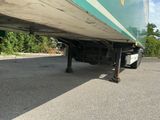 le dessous d'un semi-remorque garé sur un parking, avec des arbres en arrière-plan