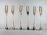 six forks are lined up in a row on a white surface
