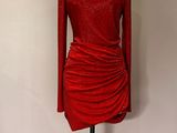 une robe rouge posée sur un mannequin devant un mur blanc