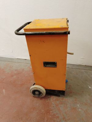 un chariot orange muni d'une poignée noire, posé dans une pièce