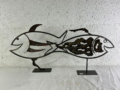 a metal sculpture of a fish that is on a stand