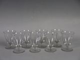 six empty wine glasses are lined up on a white surface