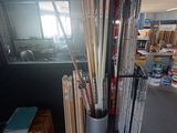 many baseball bats in a metal vase in the corner of a room