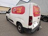 the back of a white van parked in a parking lot next to a building