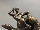 bronze statue of a man wrestling a woman on a horse