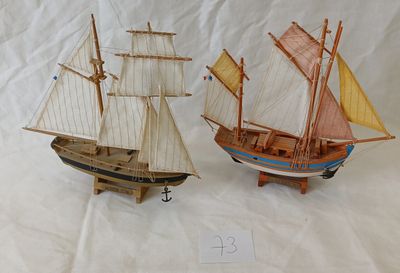deux petits bateaux en bois exposés sur une surface blanche