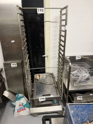 Plusieurs plateaux de nourriture sont empilés sur une étagère métallique dans une cuisine