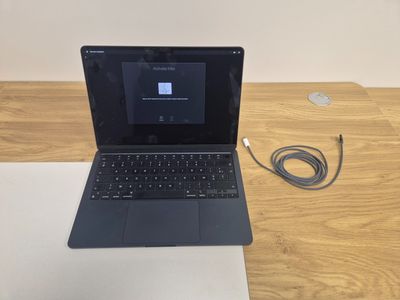 an open laptop computer sitting on top of a wooden desk next to a charger