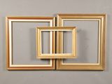 three gold frames are stacked on top of each other against a gray wall