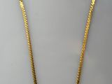 un collier en or avec une longue chaîne sur fond blanc