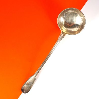 une cuillère en argent avec un manche, sur un fond orange et blanc