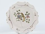 a white plate with a bird on it on a stand