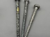 trois stylos en métal de couleur argent posés les uns à côté des autres sur une table