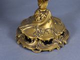 a gold candle holder with a bird on top of it