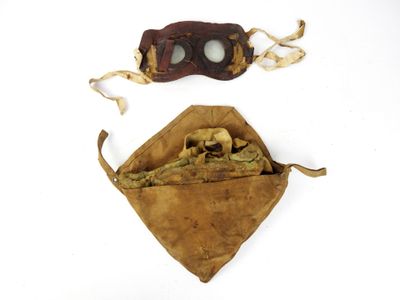 deux morceaux de cuir et une paire de lunettes de protection posés sur une surface blanche