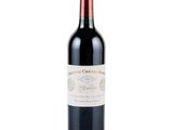the bottle of red wine is sitting on a white surface