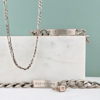 un bracelet en argent et une chaîne en argent posés sur une table blanche