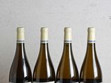 quatre bouteilles de vin sont alignées sur une table en bois