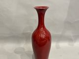 un vase rouge posé sur une surface blanche