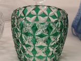 a green glass vase sitting on a table next to other glass vases