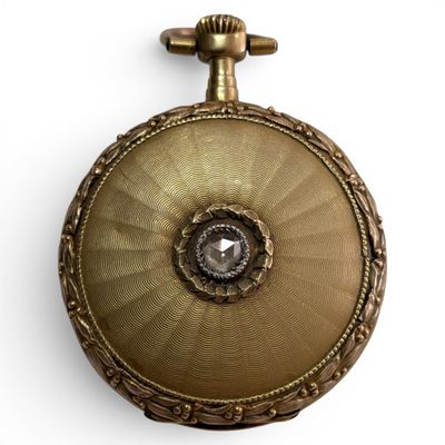 a gold pocket watch with a diamond in the center