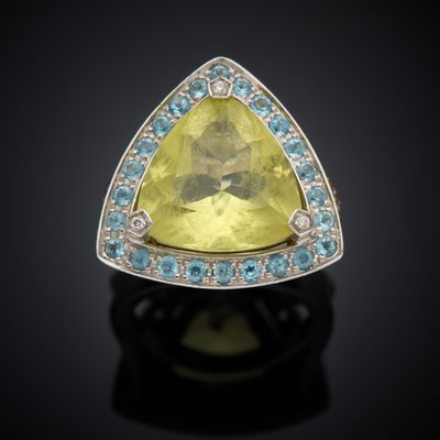 a close up of a yellow sapphire and diamond ring on a black surface