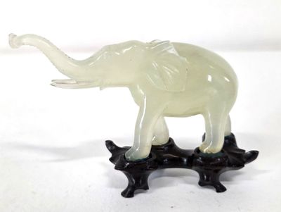 une statue d'éléphant posée sur un socle noir, sur fond blanc