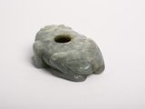 a green stone animal shaped object on a white surface