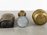 three antique brass vases are sitting on a white surface