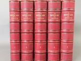 six livres rouges sont empilés les uns sur les autres sur une table
