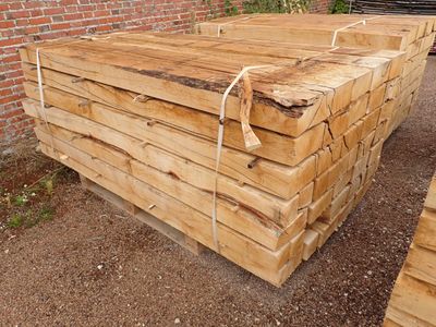 Plusieurs morceaux de bois sont empilés les uns sur les autres devant un mur de briques