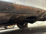 a close up of a car ' s rear end with a rusted bumper
