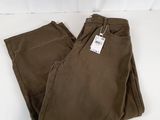 un gros plan sur un pantalon marron posé sur une surface blanche