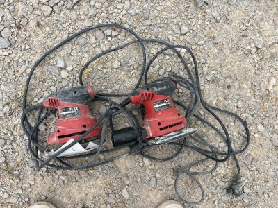two electric tools on the ground next to a pair of shoes